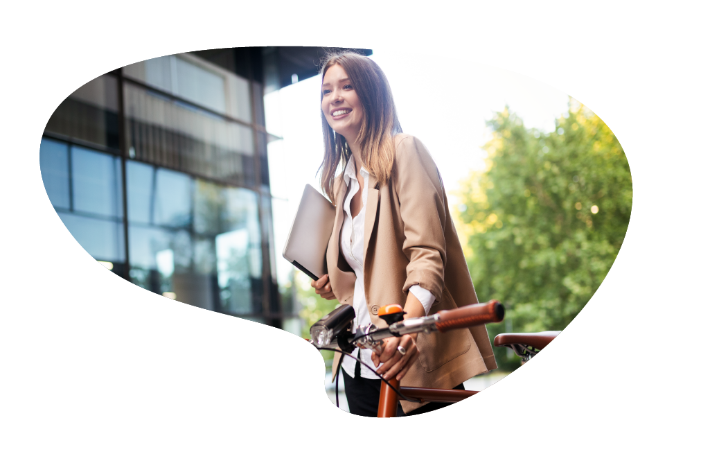Numen est engagé dans des pratiques responsables (RSE). Image d'une jeune femme, devant une entreprise, avec un fond de forêt un vélo à la main. La femme sourit et évoque le bien-être.